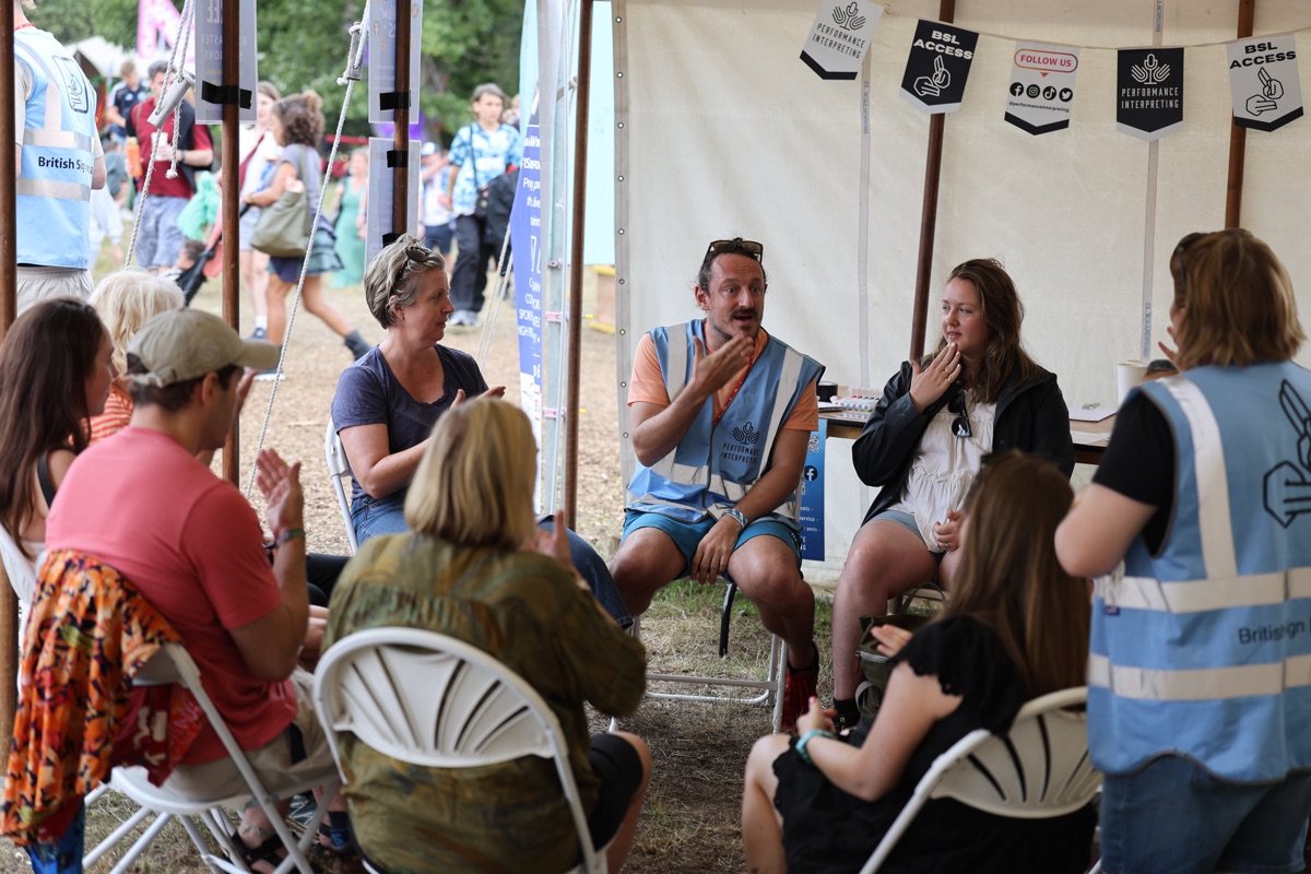 BSL interpreters and Deaf community members in a communication circle at a festival